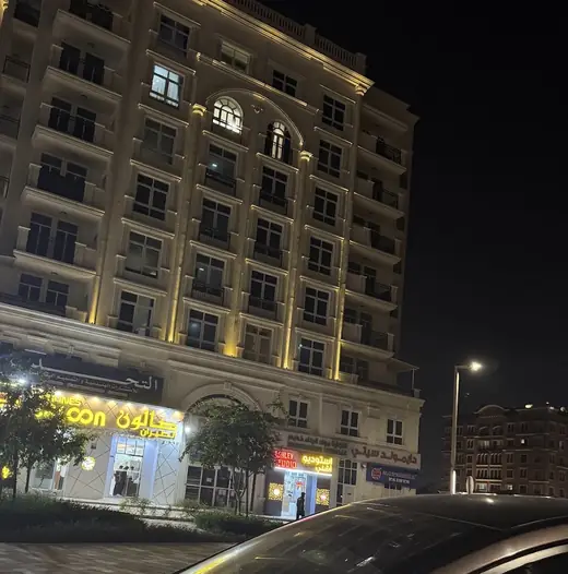 The building in SE26, Khalifa City, lit up at night, with Ashley Fotografia on the ground floor